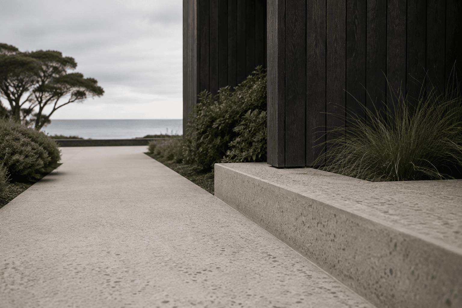 Pale aggregate path alongside dark architectural cladding